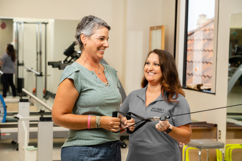 Cancer patient holding cable machine with therapist