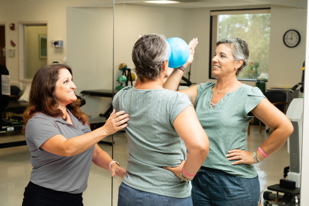 Cancer patient with hand on ball looking in the mirror