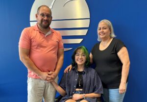 Izzy posing with her parents in front of the Brooks sign
