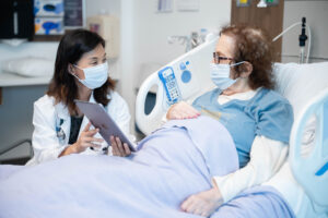 Dr. Lee at patient's bedside showing patient an ipad