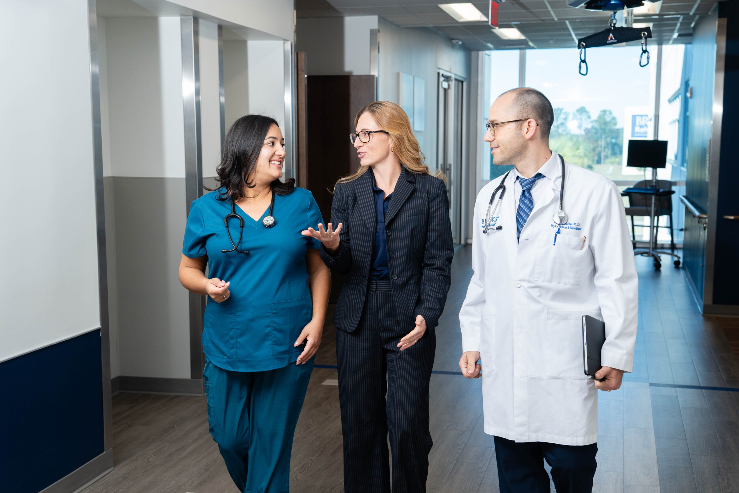 a nurse, doctor and research talking together in a hall at the Bartram campus hospital for Brooks Rehabilitation.
