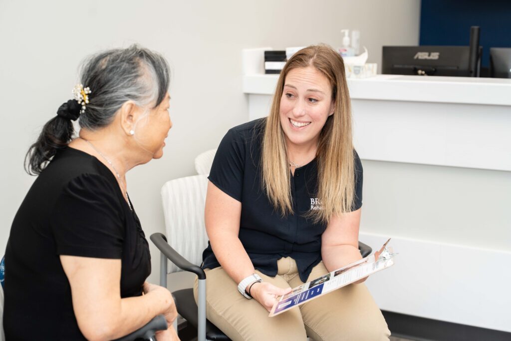 A clinical researcher is sitting next to a stroke survivor discussing how to become a research participant.
