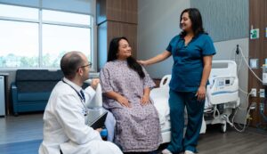 PM&R physician and rehab nurse check in on a patient in the hospital room.