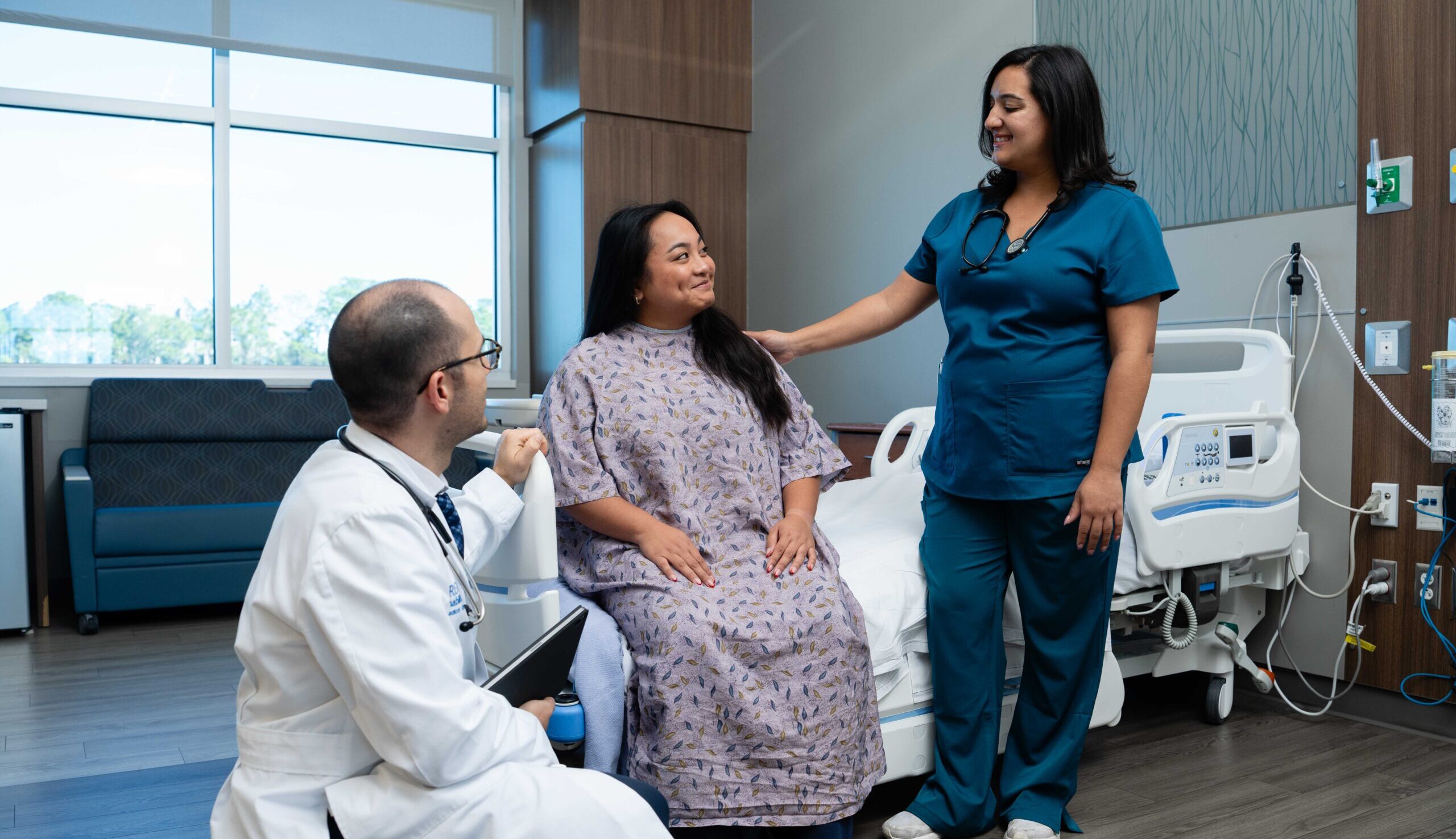 PM&R physician and rehab nurse check in on a patient in the hospital room.