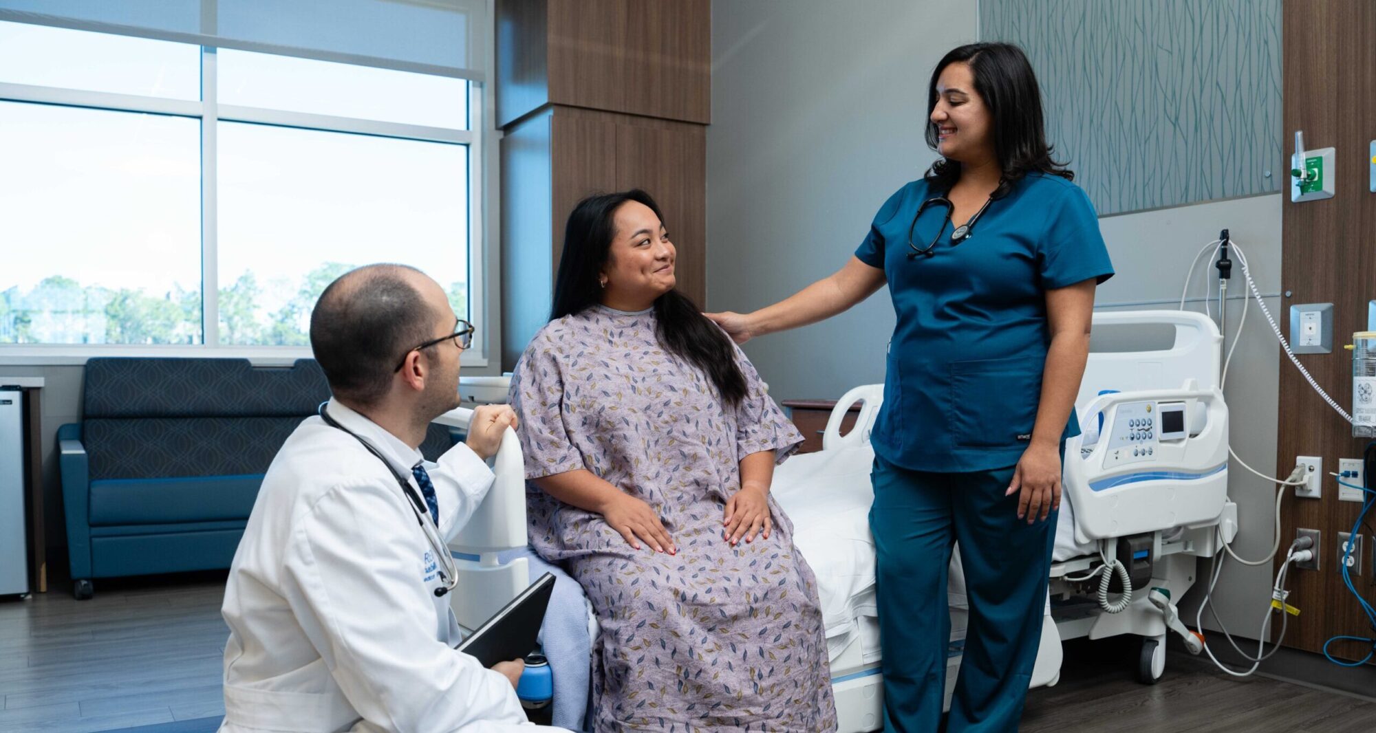 PM&R physician and rehab nurse check in on a patient in the hospital room.