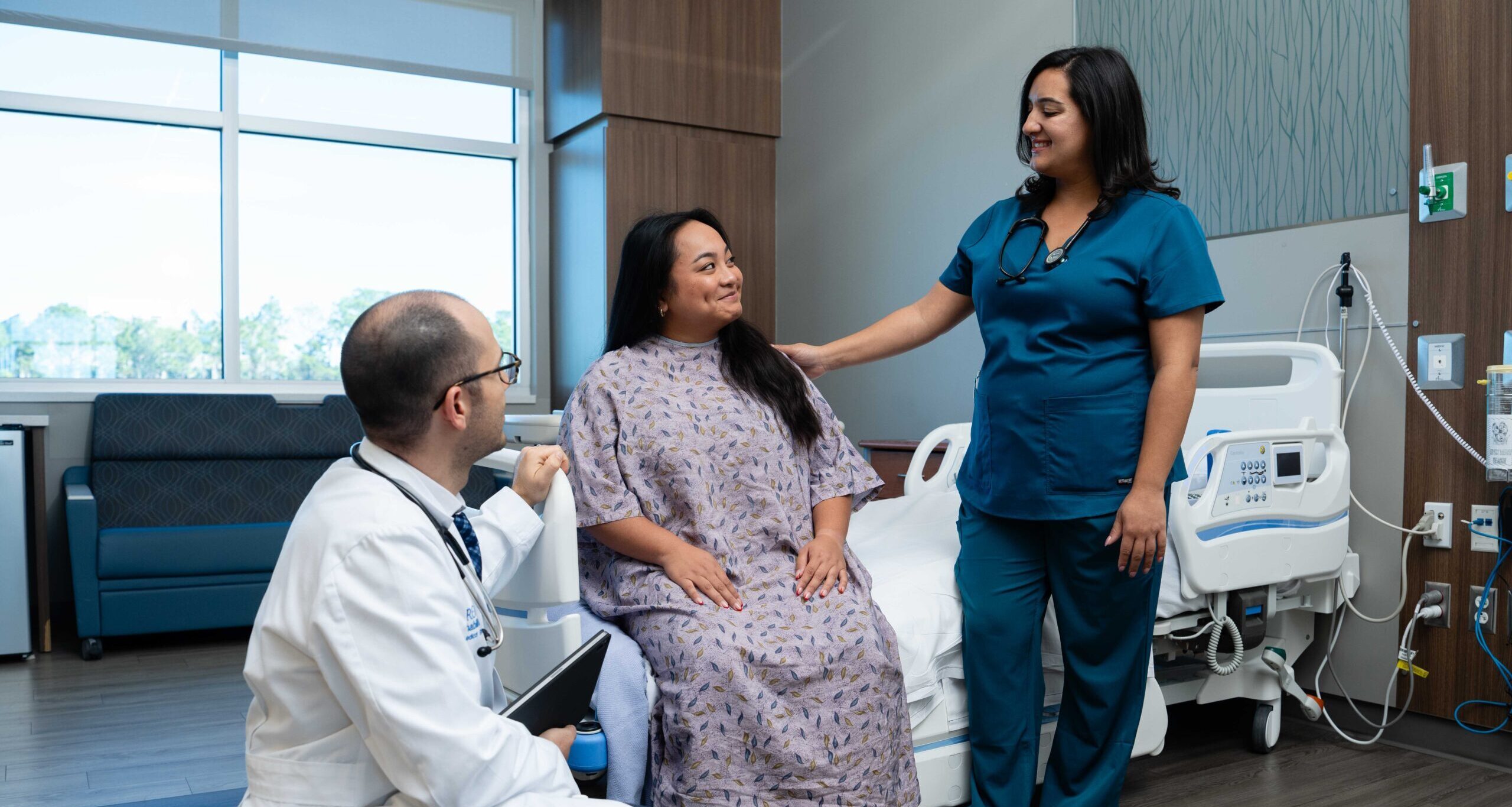 PM&R physician and rehab nurse check in on a patient in the hospital room.
