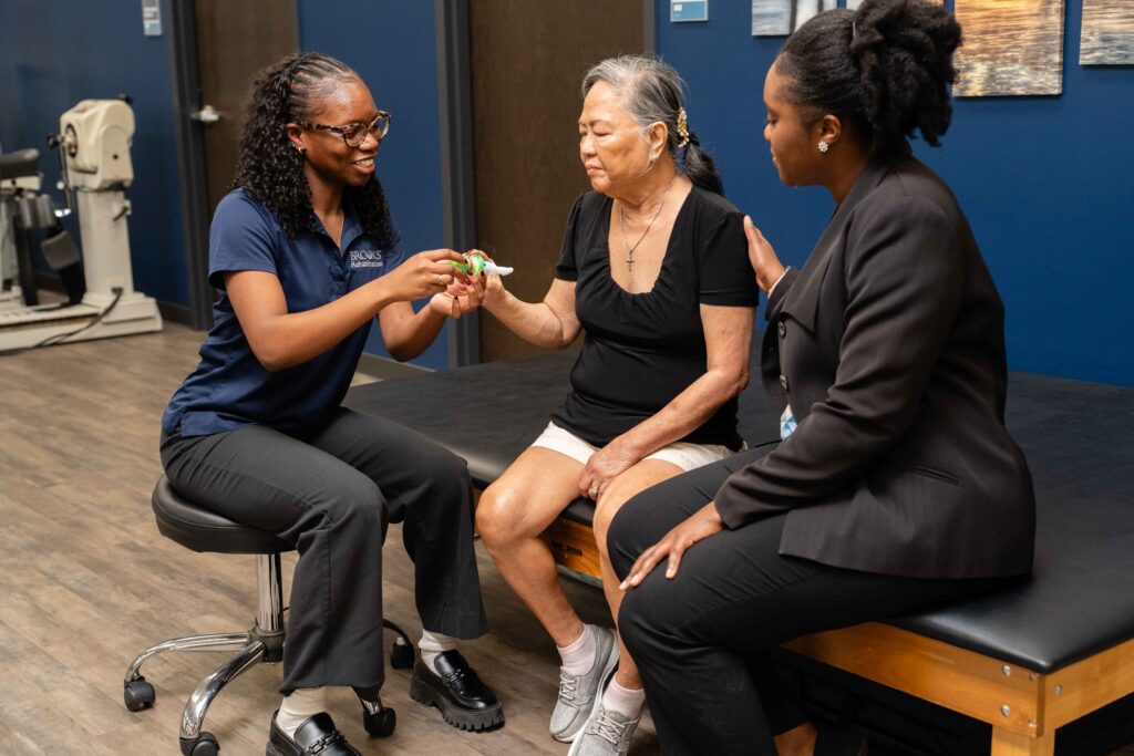 stroke patient is testing respiratory strength with two Brooks research clinicians.