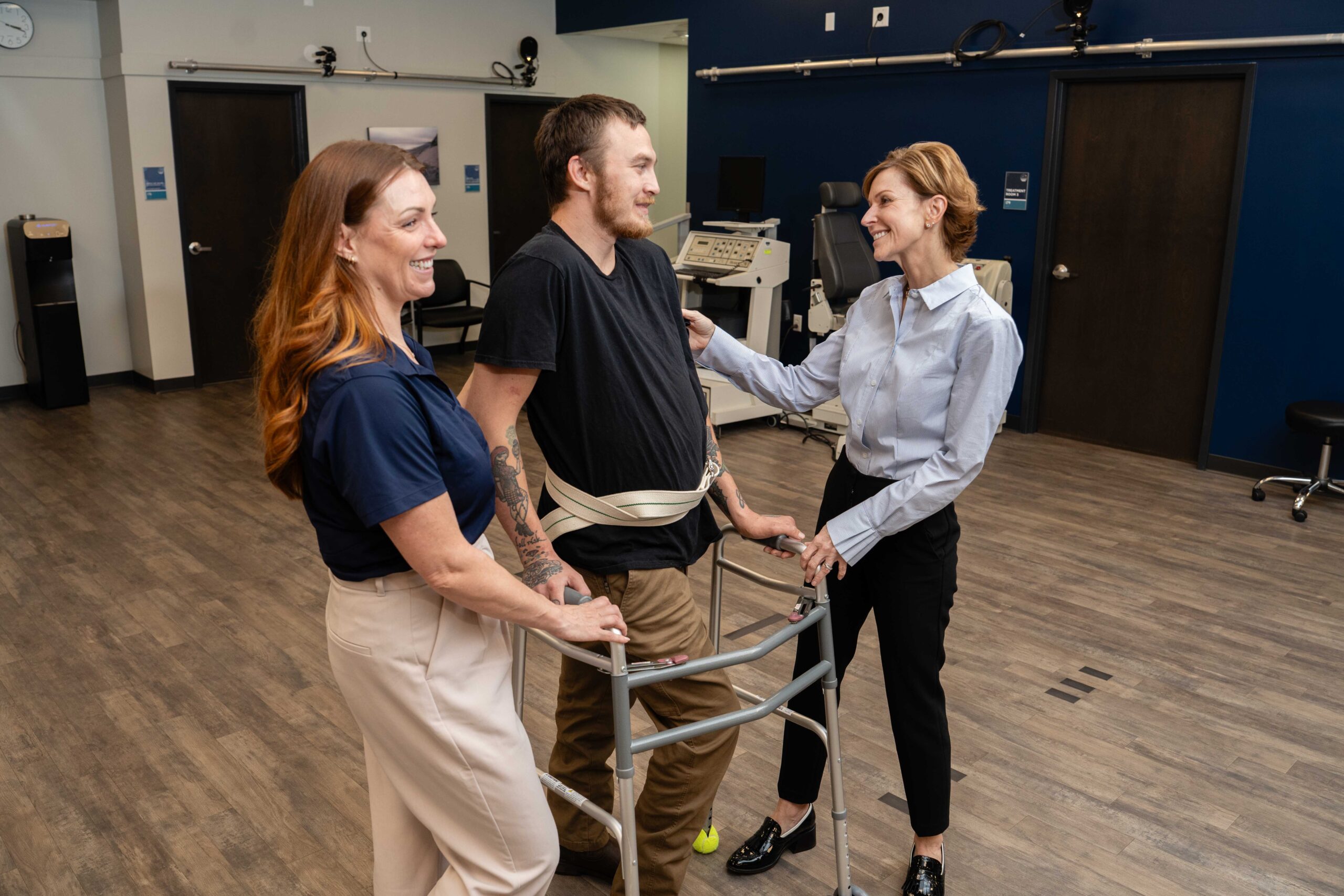 A brooks researcher and clinician support a spinal cord injury research participant as he practices walking.
