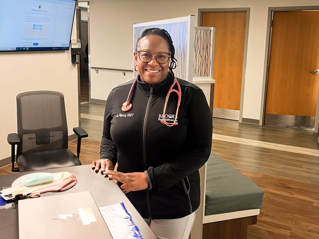 Respiratory therapists stands near a desk in a hall in a hospital.