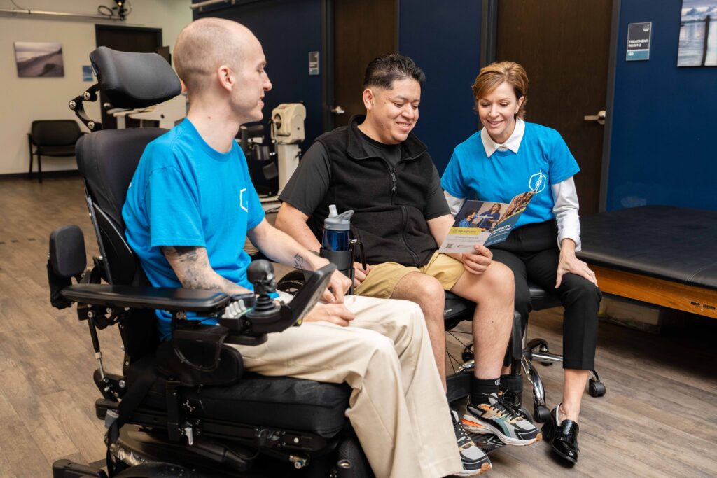 Members of the SHARP program explain the benefits to a man in a wheelchair with a spinal cord injury.