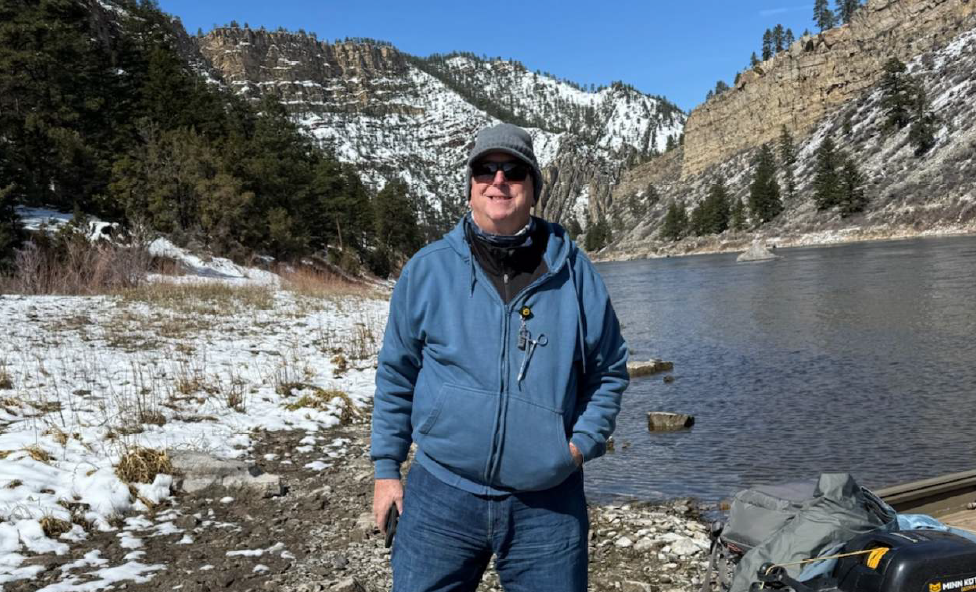 man standing in front of lake and mountains