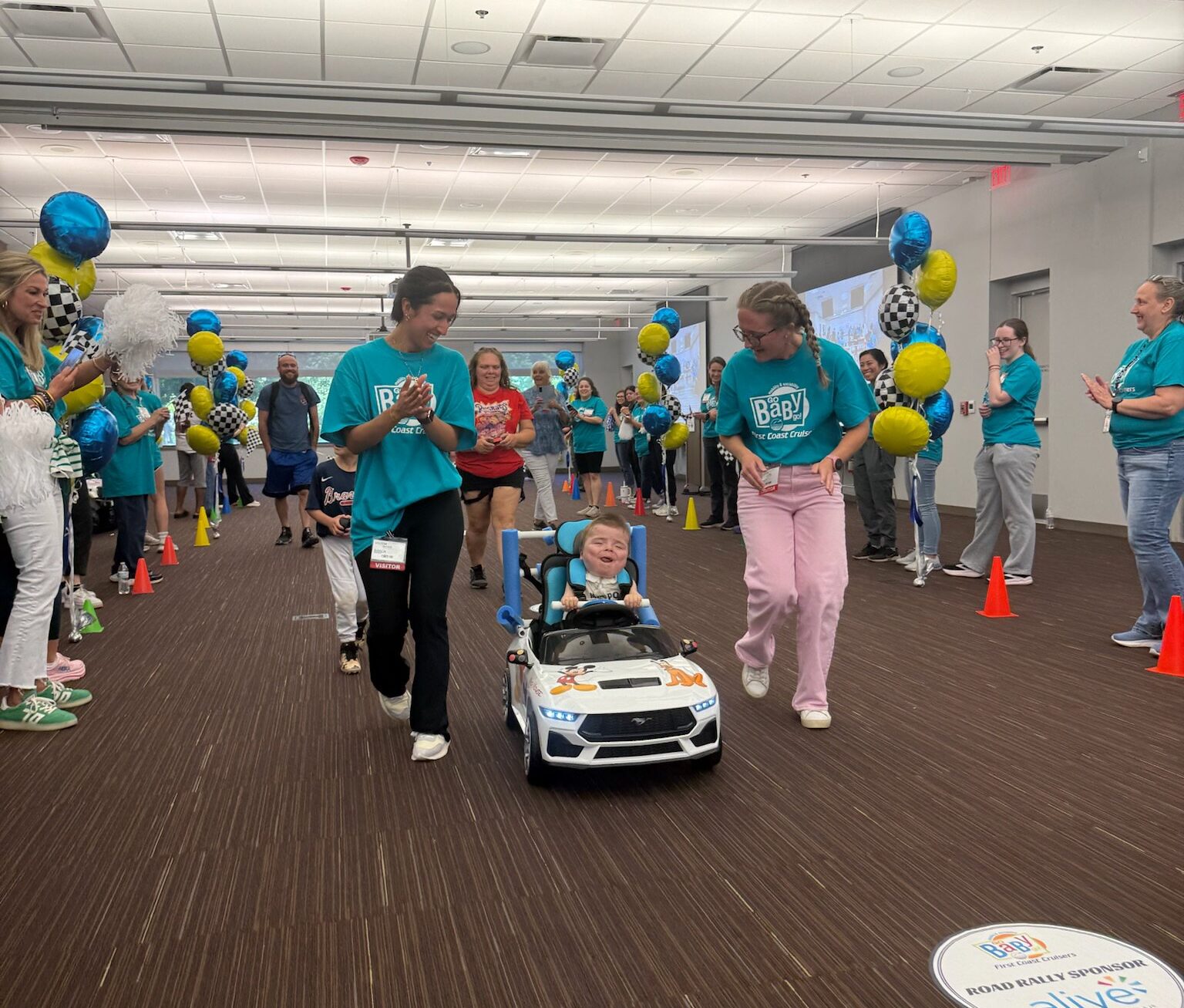 Child in car for GoBabyGo being pushed by two volunteers