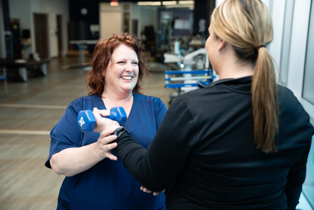 occupational therapist working on building limb strength with a patient in a therapy gym.