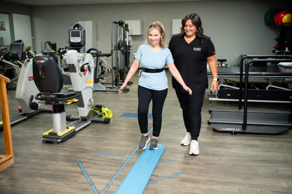 Deborah Plews walking with therapist in gym