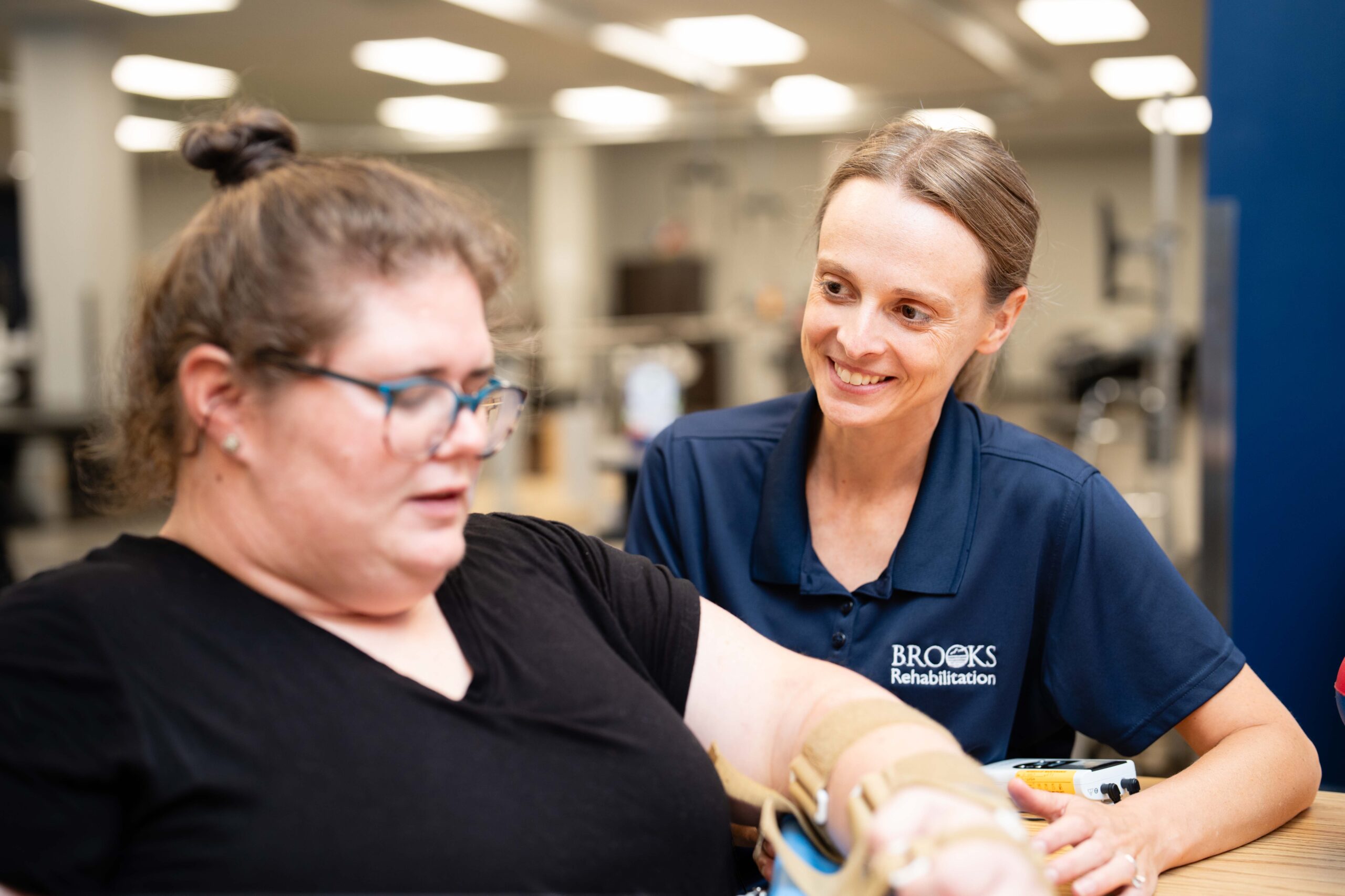 A therapists splits a female patient's arm at an outpatient clinic gym.